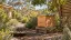Illustration of timber beehives beside flowering plants in a dry garden