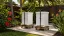Two white beehives with securing straps on low stands in a tropical backyard garden.