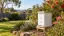 Illustrative white beehive in a Sydney garden with bottlebrush, grevillea and a corrugated fence